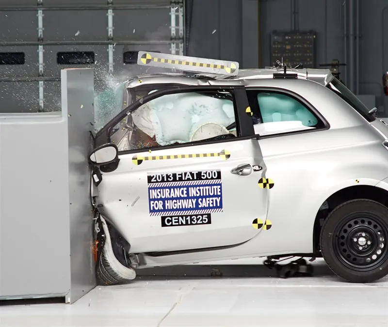 The 2013 Fiat 500 against the barrier, its driver's door open at the front edge and the airbags deployed.